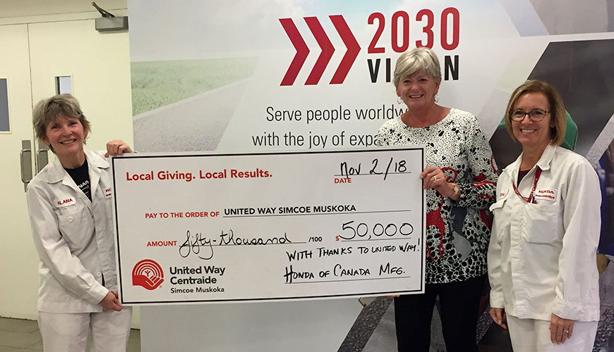 Two female Honda employees give a giant cheque for fifty-thousand dollars to United Way Centraide